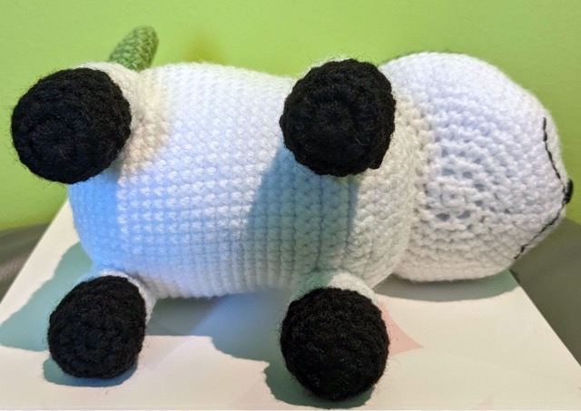 Sommie on its side with the bottom of its body and paws facing the viewer. The legs are sewn on.